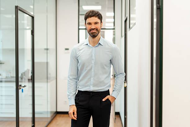 istock Confident businessman smiling in modern office corridor 2231805359