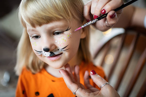glückliches kleines mädchen, das sich auf halloween vorbereitet - bemaltes gesicht stock-fotos und bilder