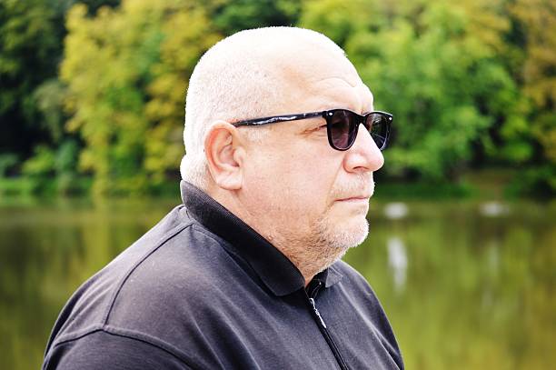 Elderly man in sunglasses against the background of a park space