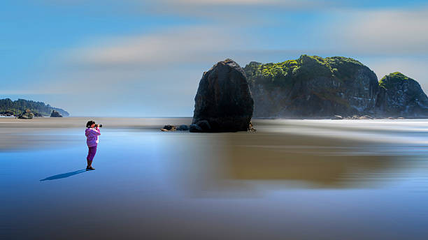 Photographer Capturing Scenic Seascape with Rock Formations on a Tranquil Beach