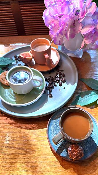 istock Rustic wooden surface holding three coffee cups, chocolate, figs, coffee beans near purple flower vase, radiating warm, welcoming mood 2231810895