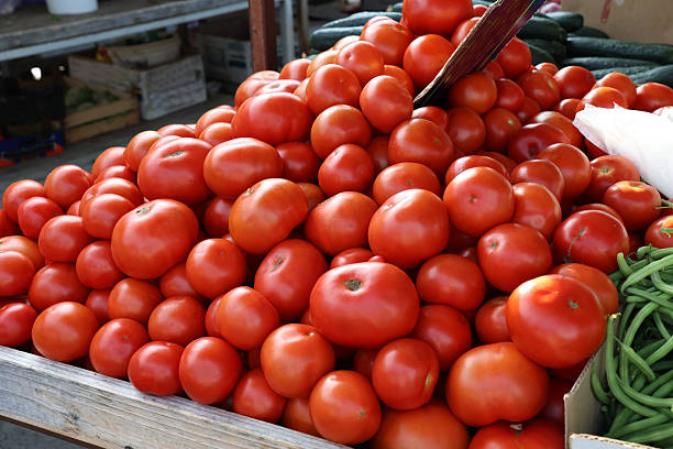 Hands selecting tomatoes on a counter at the organic city market.