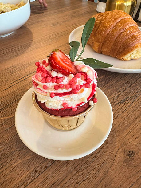 Delightful strawberry cupcakes topped with a luscious whipped cream and garnished with fresh ripe strawberries, creating a harmonious fusion of taste and aesthetics perfect for summer indulgence