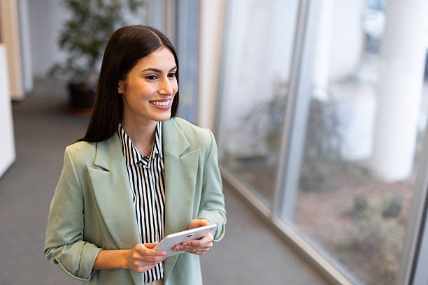 istock Professional businesswoman navigating sleek corporate workspace, holding digital tablet and expressing confident demeanor 2231814821
