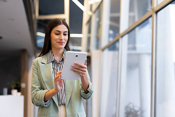 istock Young businesswoman walking through a modern office space, engaging with a digital tablet and embodying confidence and professionalism 2231816664
