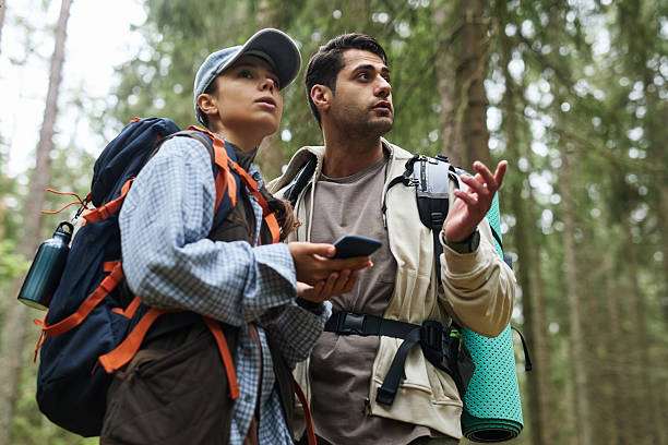 istock Young Caucasian Man and Woman Exploring Forest with Smartphone and Backpacks 2231817644