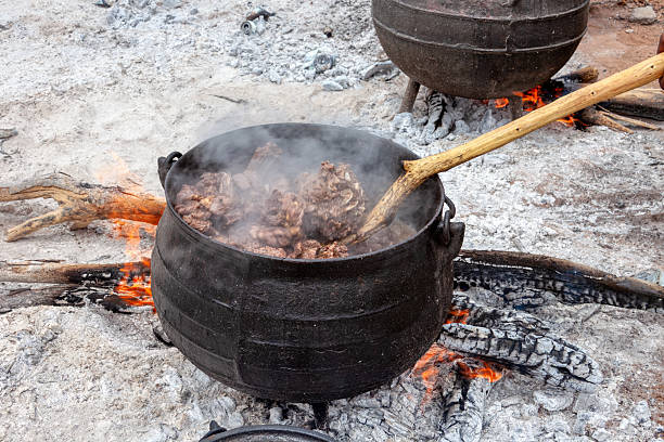 istock african village boiling beef meat in a cauldron three legged pot outdoors kitchen, event cooking in the village, wood fire and ashes 2231818059