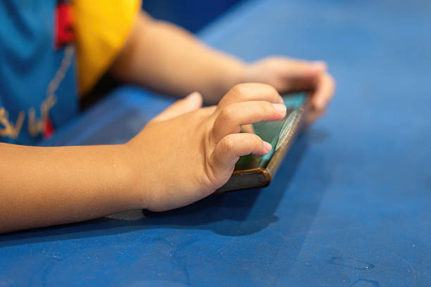 Phone in hands of child. Little boy playing mobile games on smartphone. Hand closeup..