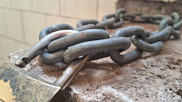 Chain and padlock securing a brick, symbolizing strength, restriction, and protection in a simple security concept.