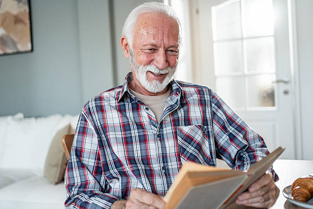 istock Happy senior man reading a book at home 2231827009