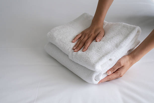 istock Hands placing a stack of new and clean bath towels on a bed. 2231828860
