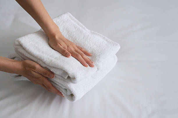istock Hands placing a stack of new and clean bath towels on a bed. 2231828863