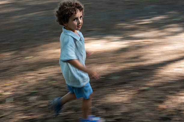 Boy running on dirt road in forest.