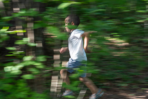 Cute little boy jogging thought the forest.