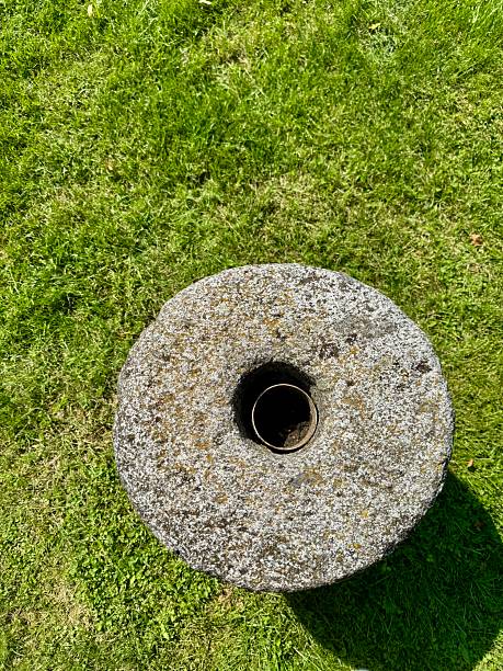 istock Old stone mill wheel on green grass 2231836276