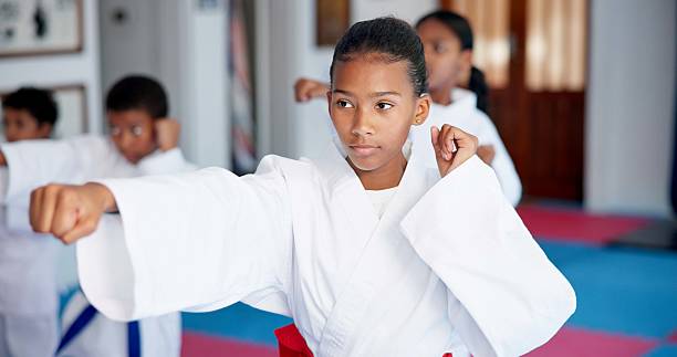 istock Punch, lesson and girl in karate dojo for self defense training, challenge or skill with martial arts. Children, female student and group for fight, class and taekwondo club with fitness or sports 2231839190