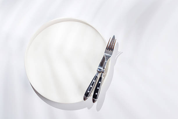Empty plate on a white background with leaf shadows, perfect food mockup. Flat lay with copy space