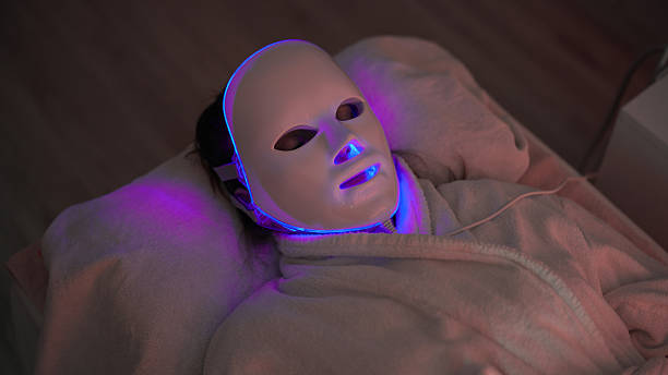 Woman receiving LED light mask therapy at beautician