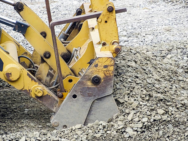 A backhoe loader works with a pile of stone