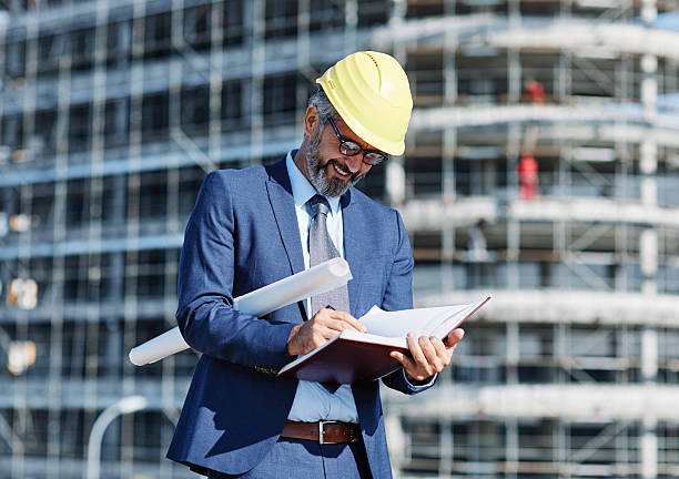 istock senior businessman architect helmet construction site building architecture writing notebook protective workwear blueprint plan 2231864278