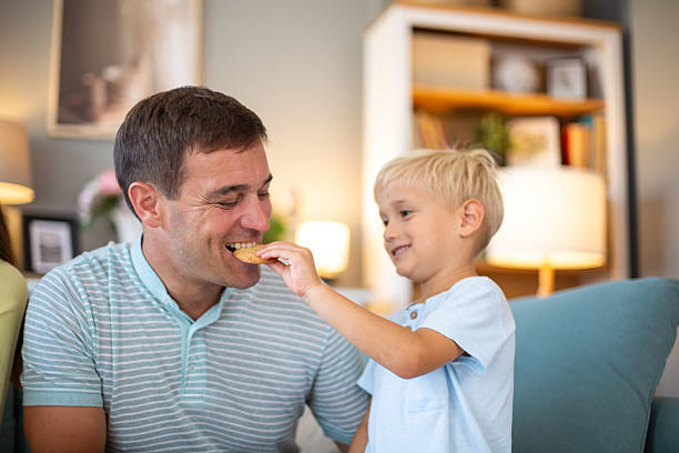 istock Caring child sharing cookie with father at home 2231864688