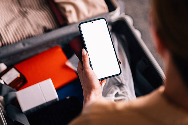 istock Person Holding Smartphone With Open Suitcase in Background 2231869232