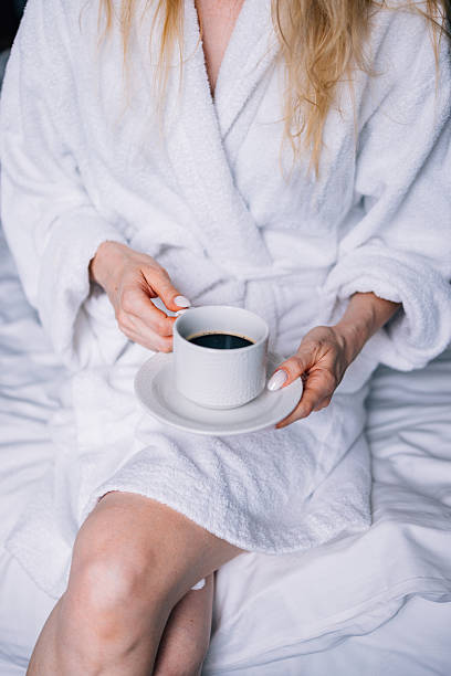 istock Woman Relaxing With Coffee in a White Bathrobe on a Bed 2231869253