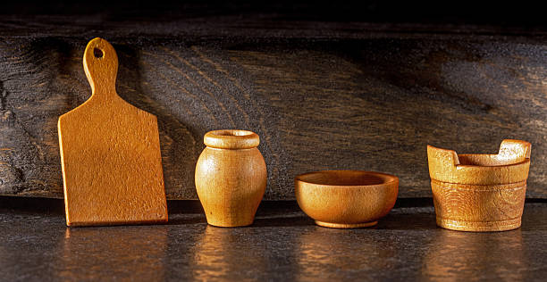This vintage wooden miniature tableware set features intricately carved plates, cups, and utensils, beautifully arranged against a dark background, highlighting the craftsmanship and timeless appeal.