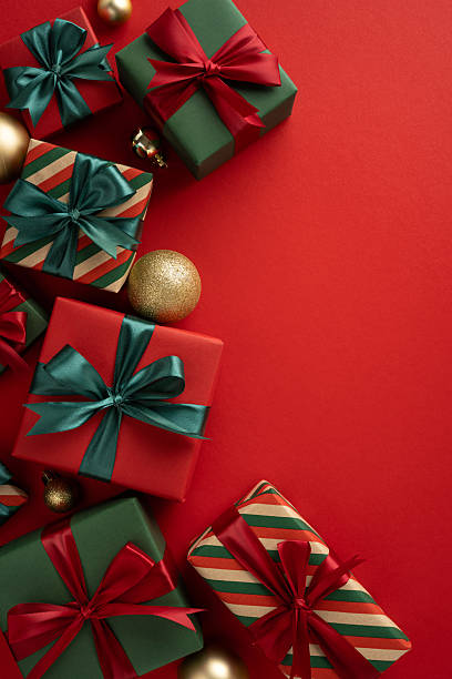 istock Colorful wrapped Christmas presents arranged with festive vertical decorations on a vibrant red background. Perfect for holiday celebrations, gift-giving, and festive season designs 2231879827