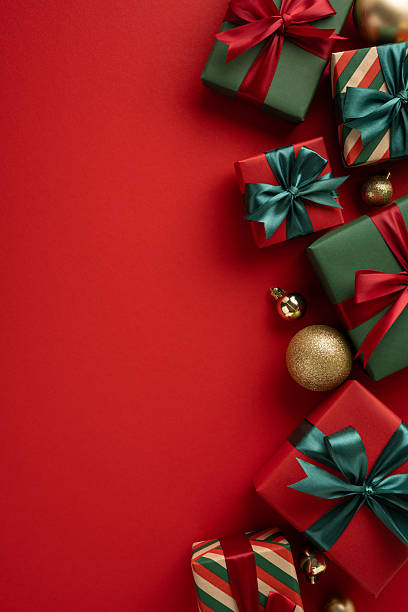 istock Christmas vertical gift bundles decorated with vibrant bows alongside ornaments on a red backdrop 2231879833