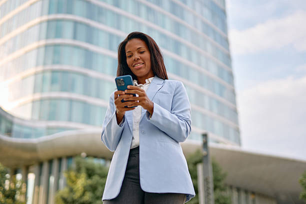 istock Businesswoman using smartphone in front of modern office building 2231886222