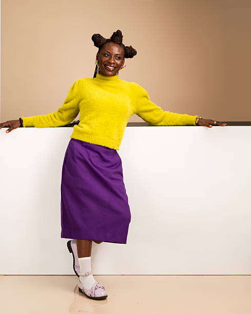 Smiling African woman leaning casually against white wall