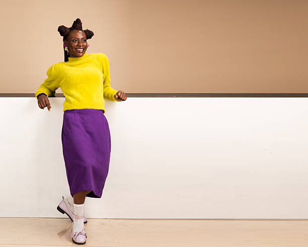 istock Smiling African woman leaning casually on white wall in studio 2231887587