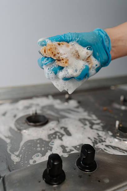 istock Vertical cropped shot of man wearing protective gloves squeezing soapy water from sponge during cleaning dirty gas stove, to removing stubborn grime and grease. 2231896126