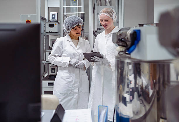 istock Young Caucasian Pharmacy Workers Collaborating in Laboratory Wearing White Coats and Hairnets 2231897248
