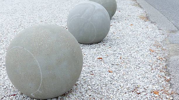 Three oversized concrete spheres positioned on a gravel surface, showcasing a contemporary outdoor installation with a focus on minimalist urban design