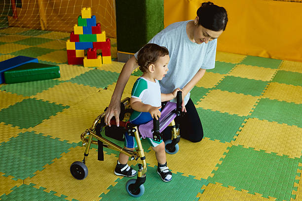 istock Handsome young boy with movement disorders practices walking with support from a therapist in rehabilitation clinic 2231901523