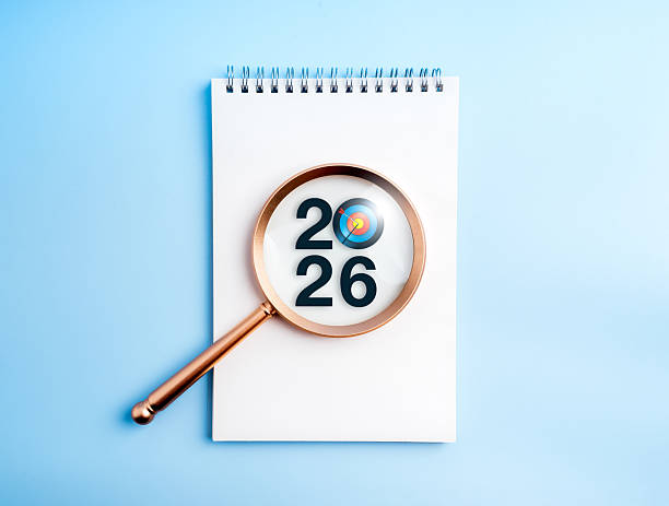 istock Magnifying glass focusing on year 2026 with target symbol on notepad, representing New Year goals, business trends, future vision, resolution planning, innovation strategy, goal setting and ideas. 2231909207
