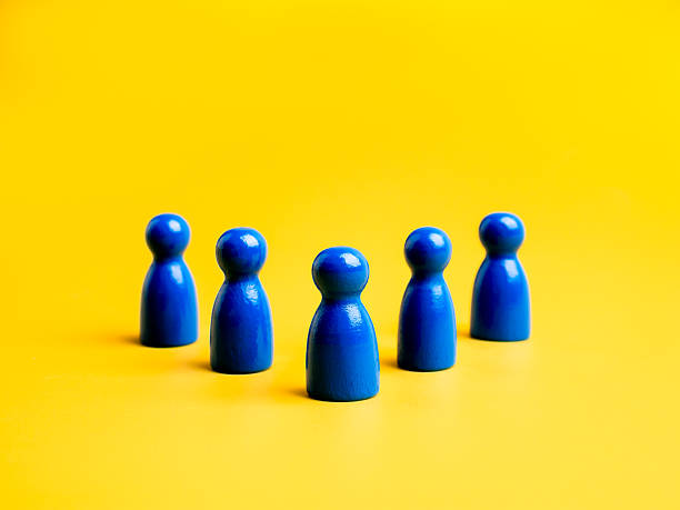 istock Blue wooden figures arranged in formation on yellow background, representing teamwork, leadership, team building, innovation, and collaboration in creative or technology-driven business environments. 2231909251