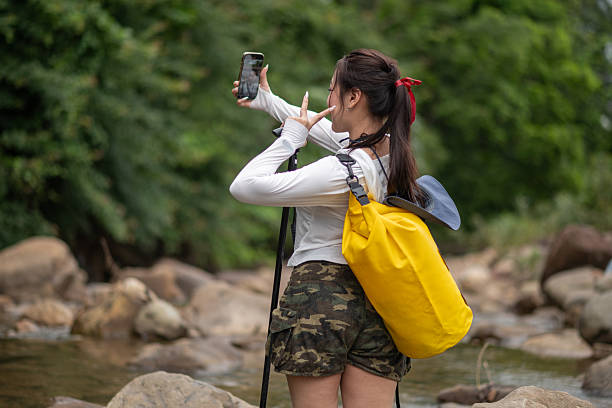 istock Woman is exploring nature enjoying holding and looking at a smartphone , possibly using selfie, reading, or recording journey representing  nature and modern technology. 2231911146
