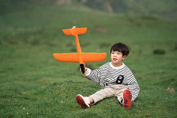 Asian three-year-old child playing with airplane model on the grassland