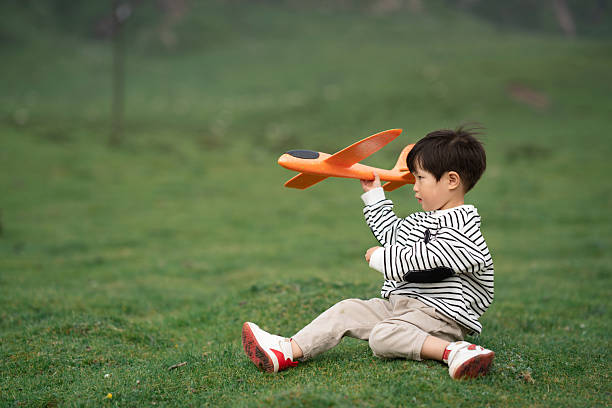 Asian three-year-old child playing with airplane model on the grassland