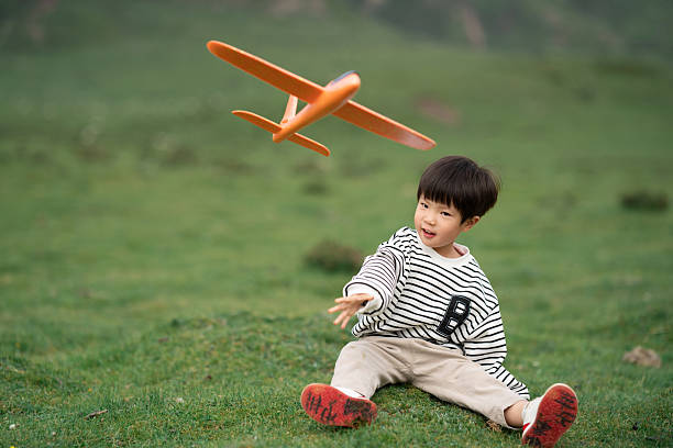 Asian three-year-old child playing with airplane model on the grassland
