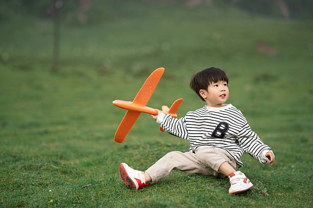 Asian three-year-old child playing with airplane model on the grassland