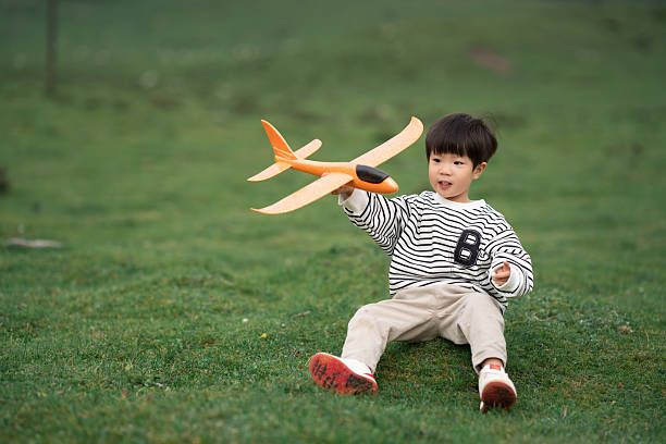 Asian three-year-old child playing with airplane model on the grassland