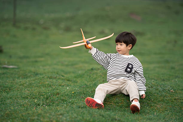 Asian three-year-old child playing with airplane model on the grassland