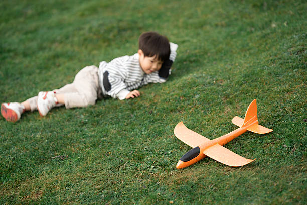Asian three-year-old child playing with airplane model on the grassland