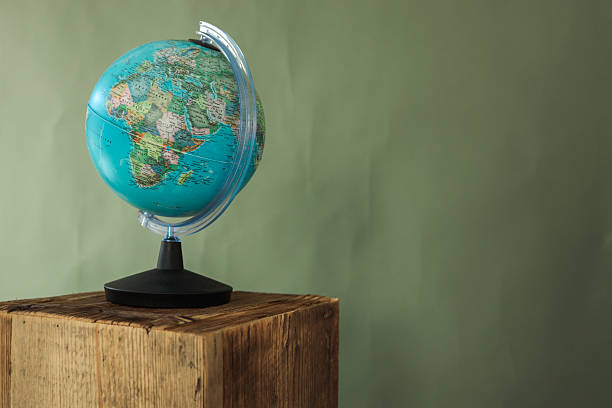 istock Colorful world globe placed on rustic wooden pedestal with green background, symbolizing geography, travel, and education 2231921097