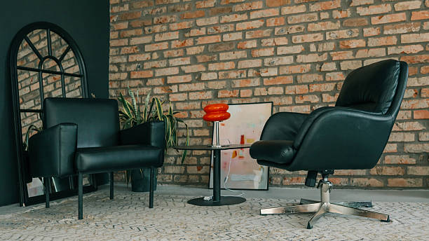 istock Modern loft interior with black leather chairs, brick wall, decorative plants, and stylish table lamp creating cozy atmosphere 2231921127