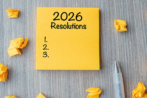 istock 2026 RESOLUTIONS word on yellow note with pen and crumbled paper on wooden table background. New start, Strategy and Goal concept 2231922475